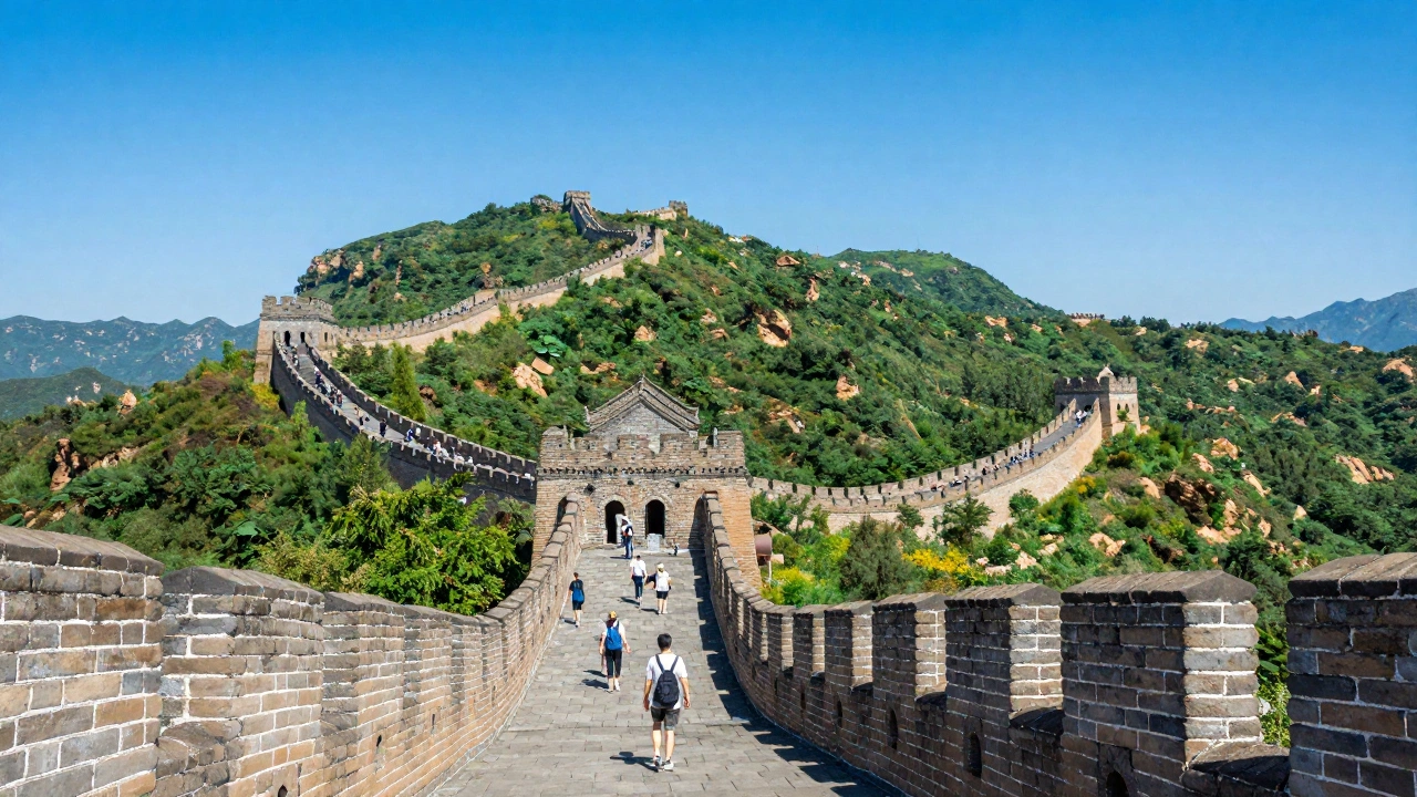 A panoramic view of the Great Wall of China snaking over lush green mountains under a clear blue sky, with hikers walking along the ancient stone path, capturing the vastness and historic grandeur of the scene.